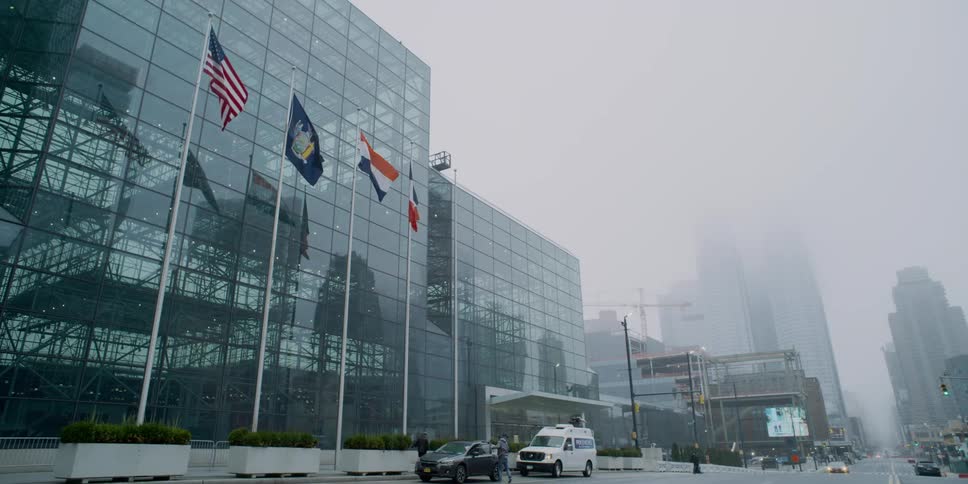 Vehicle parks by glass building on foggy day