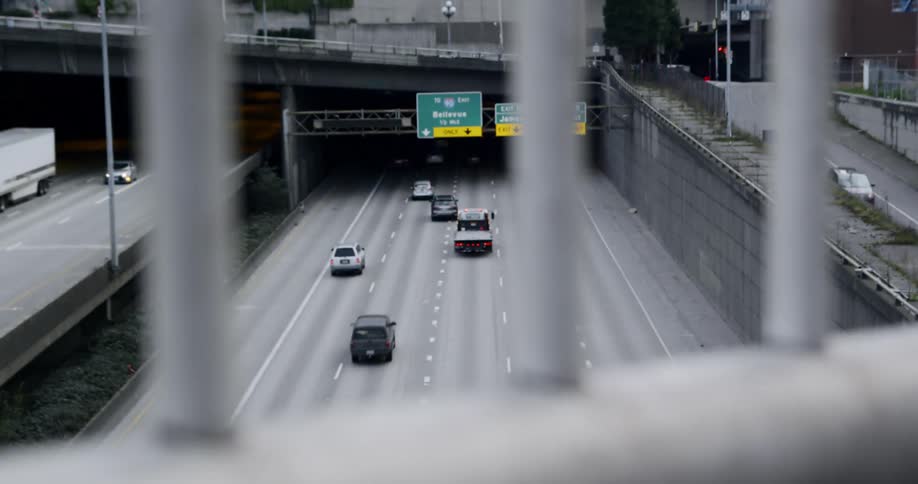 View of cars traveling on freeway from in between overpass barrier