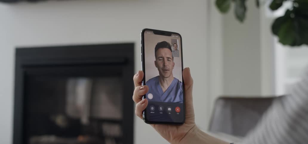 Person having a video call with a medical practitioner while sitting in room with fireplace