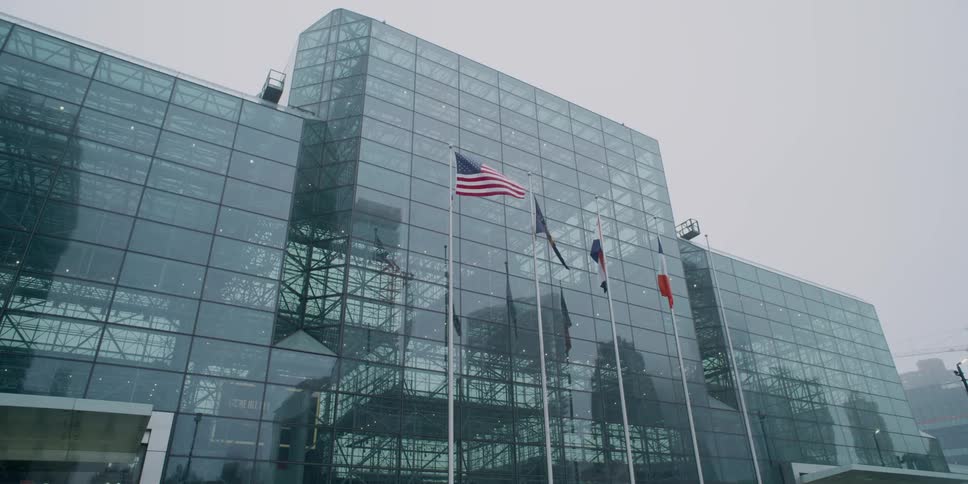 Flags fly outside of a large glass building