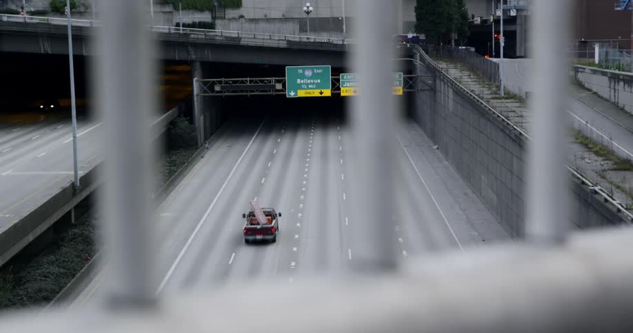 A few vehicles drive down an urban highway