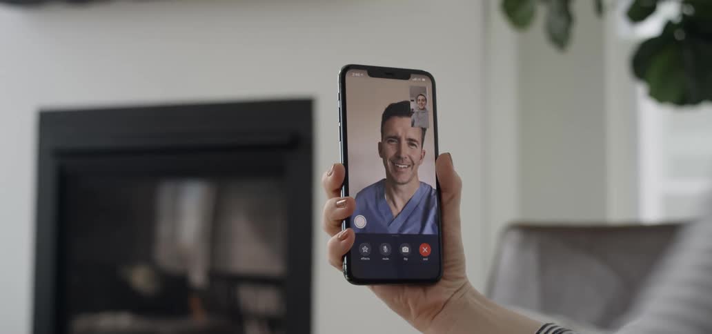 A person uses a smartphone to video chat with a doctor