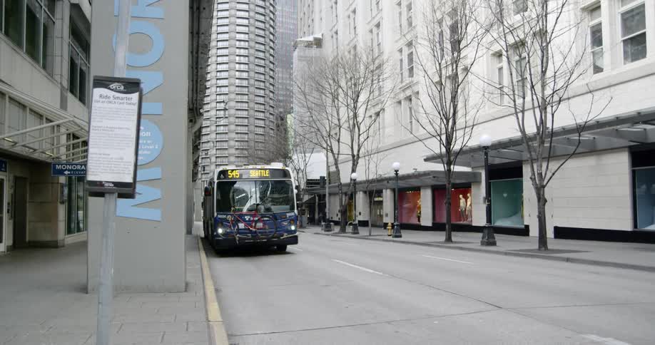 A city bus carrying a bicycle on the front of it drives down a city street