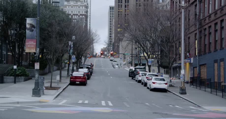 Cars drive along and line a city street