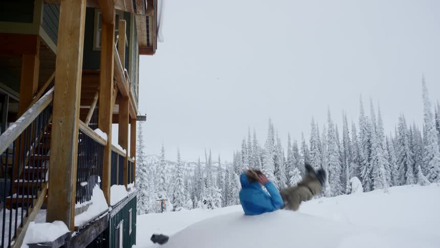 A man does a front flip off a balcony into a deep pile of snow