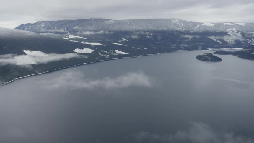 A dark lake sits nestled between snowy mountains