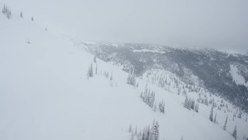 View from a helicopter flying over a snowy mountain slope