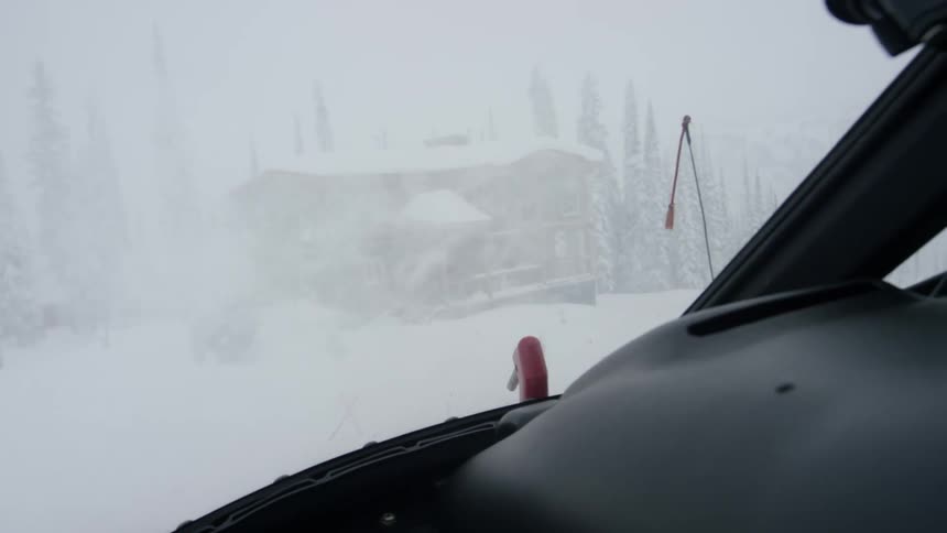 Helicopter landing near mountain building kicks up snow