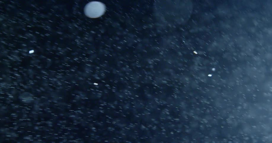 Snow falls in the night sky