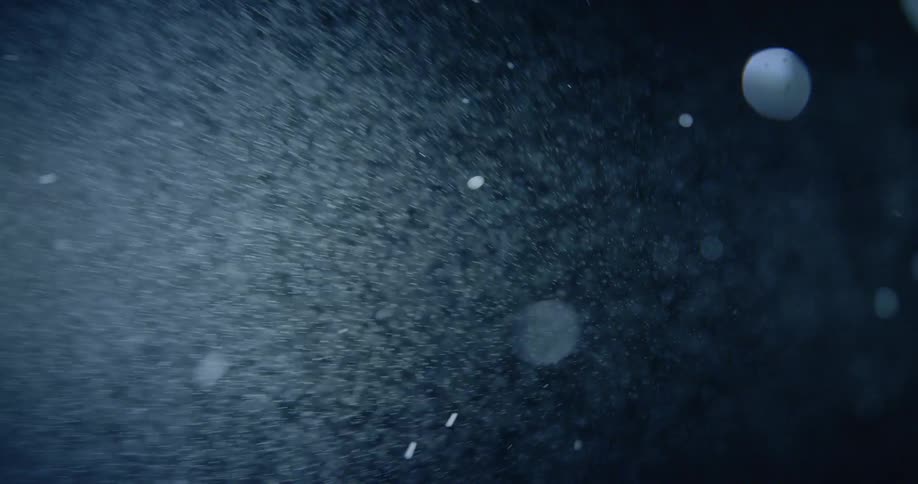 Snowflakes shimmer in a light beam at night
