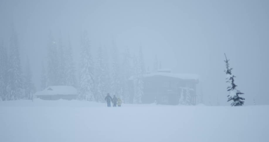 People are moving through the snow towards a cabin