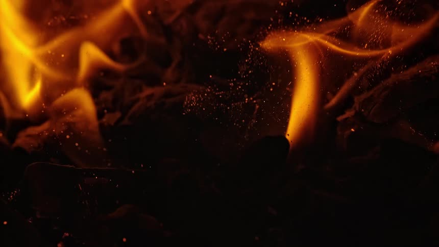 Sparks and flames rise off of logs