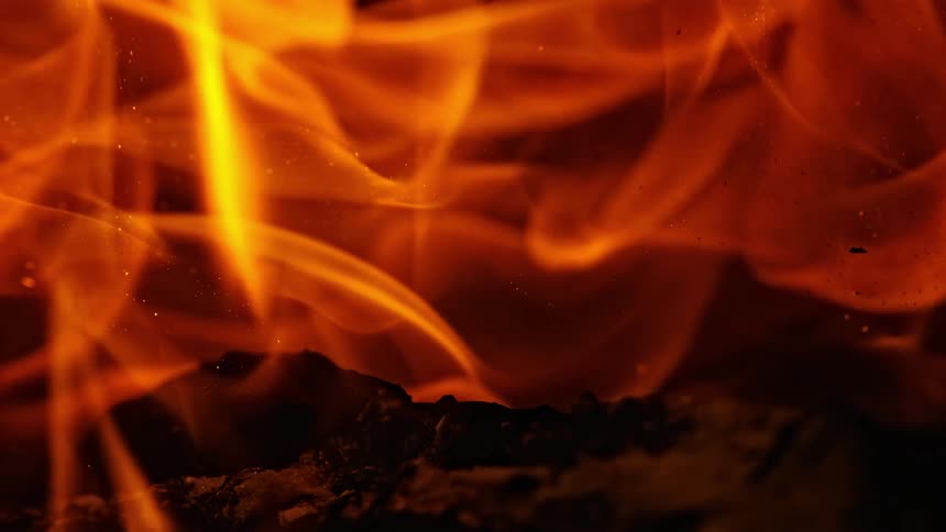 Sparks and embers rise as orange flames glow