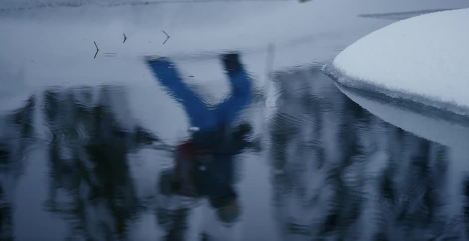 Reflection of cross country skier walking by on a melted snow puddle