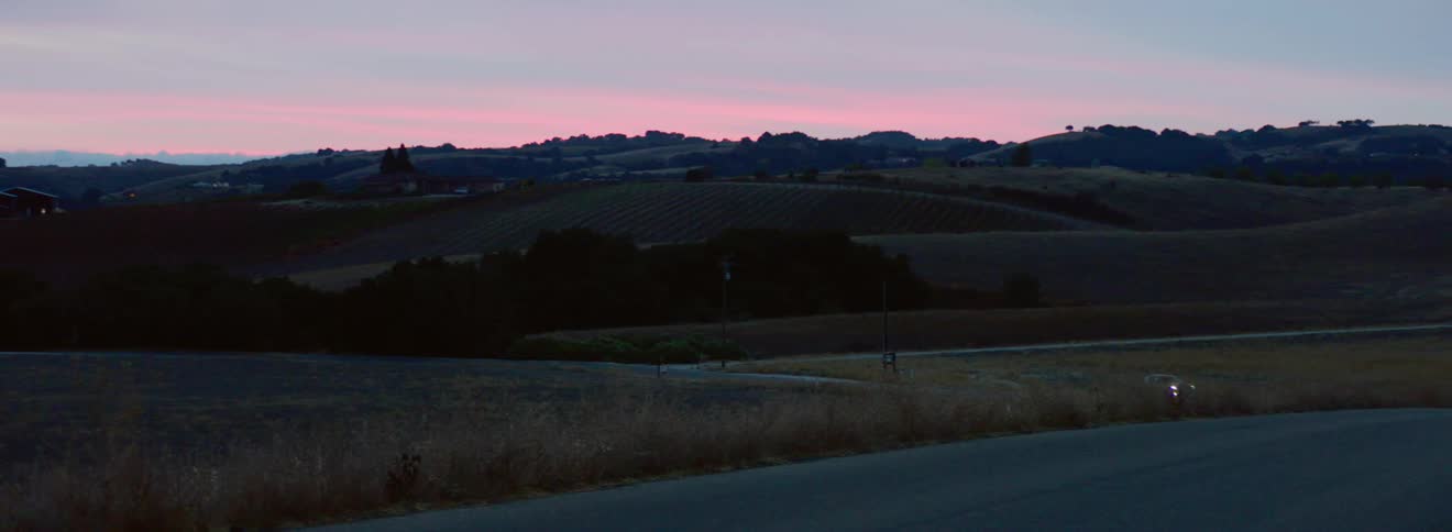 Truck driving on a country road in the distance at sunset