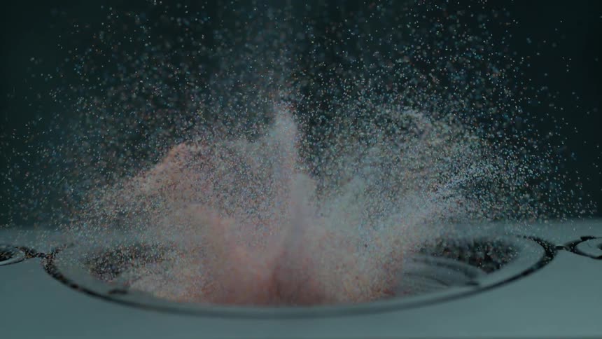 Colored particles fly up in the air as a speaker moves