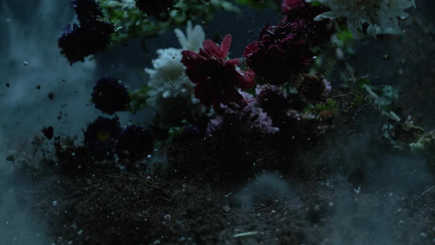 A bouquet of flowers falls onto the dirt pile