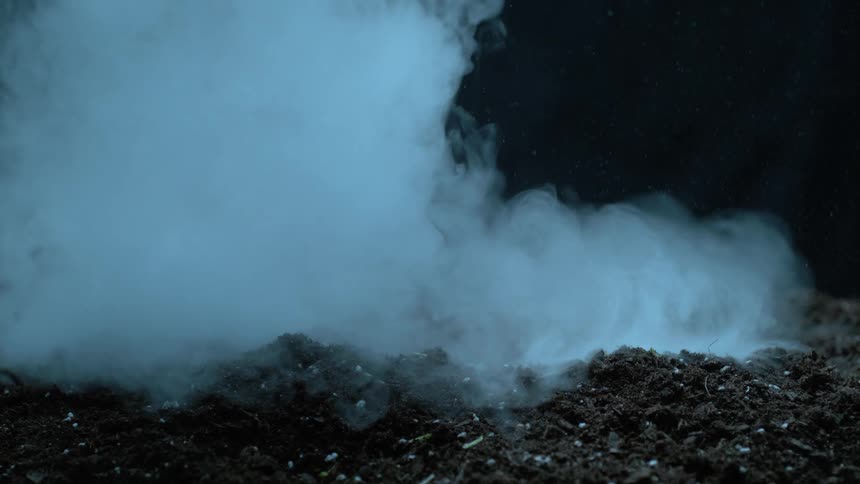 Clouds of white flow down and spread across the dirt ground
