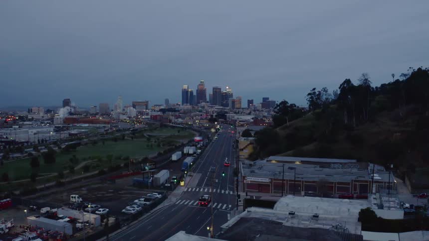 Cars drive on a highway into a city at sunset