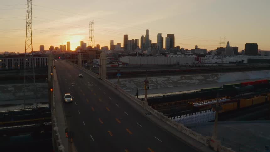 Aerial view of two cars driving down a quiet freeway with a city in the distance