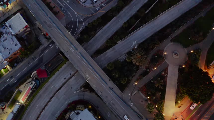 Birds fly over the empty highways and streets of a city while a police cars lights flash