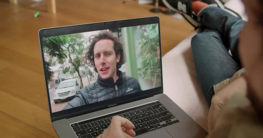 Man sitting on the sofa makes a video call with his friend on the laptop