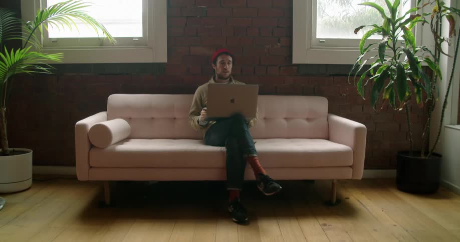 A young white man talks to someone through a laptop computer