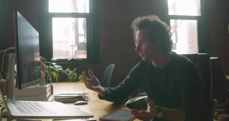 A white man has a conversation with someone over a computer connection