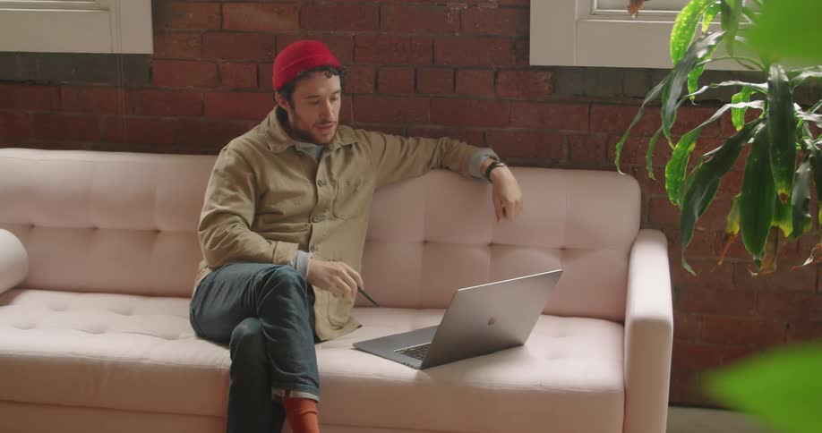 A person is using a laptop and sitting on a couch