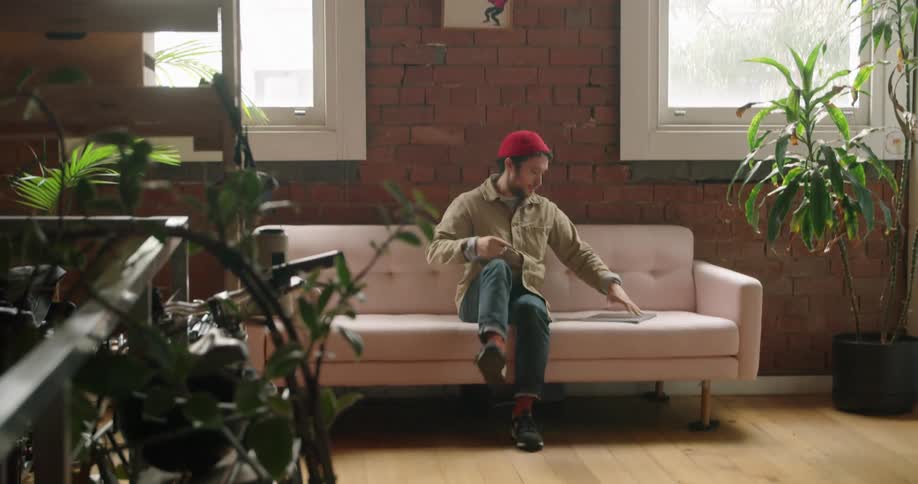 Man sitting down on the couch uses a laptop at home
