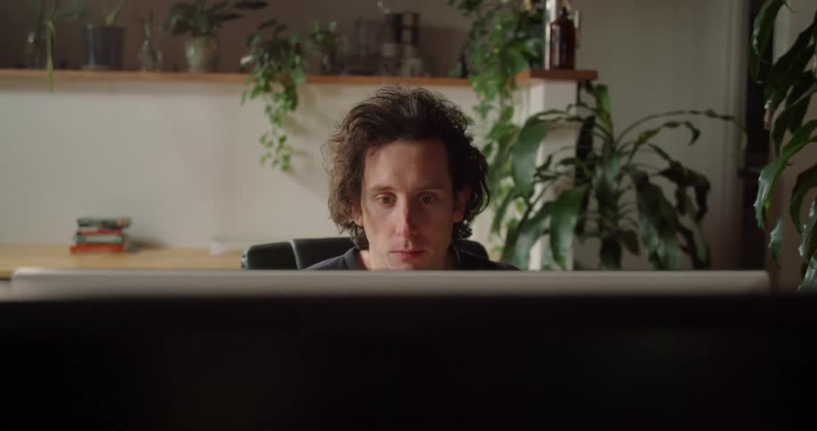 A man sitting at a desk with plants in the background