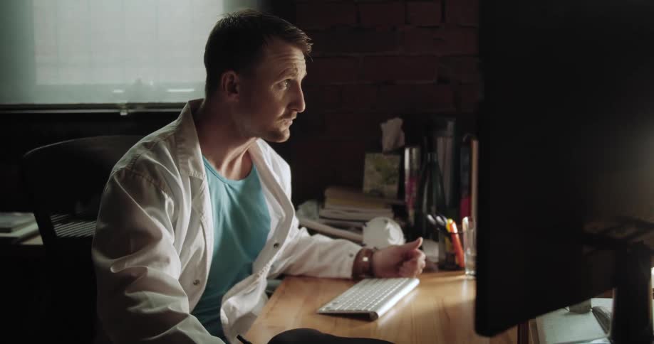 A man in a lab coat takes notes on a pad of paper