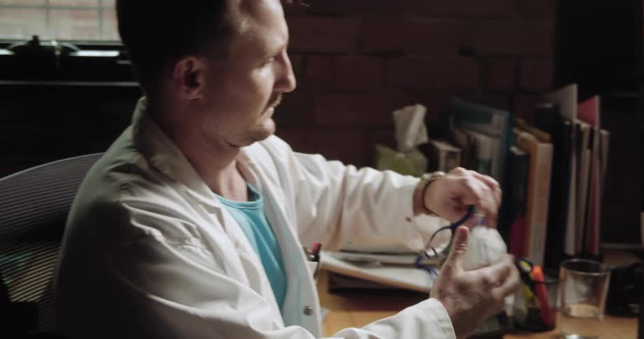 A young doctor talks on a smartphone and then puts on a face mask and leaves quickly