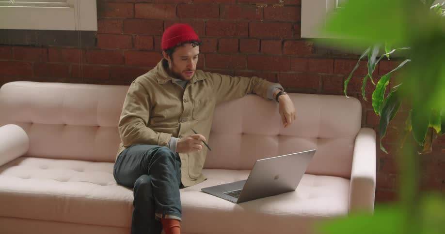 Man sits on couch teleconferencing on laptop