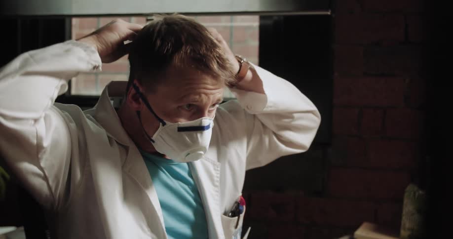 A doctor puts on a face mask and leaves his office
