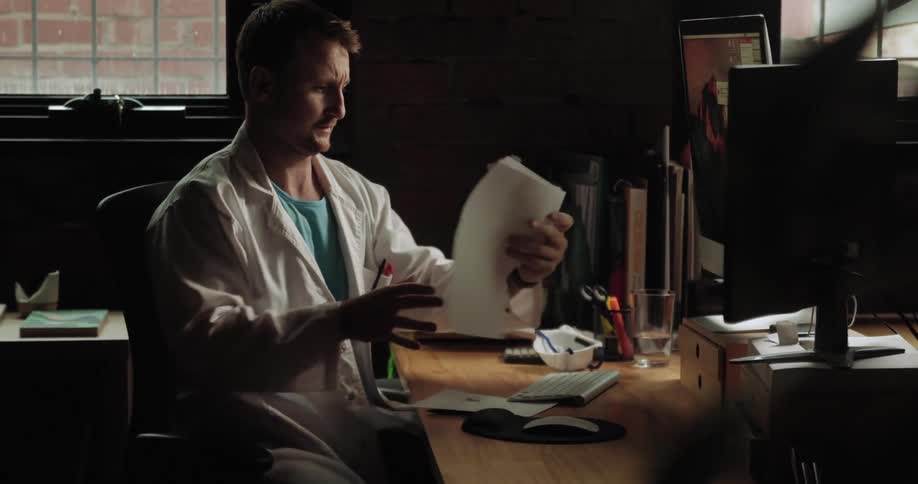 A doctor taking off his mask and looking at a paper
