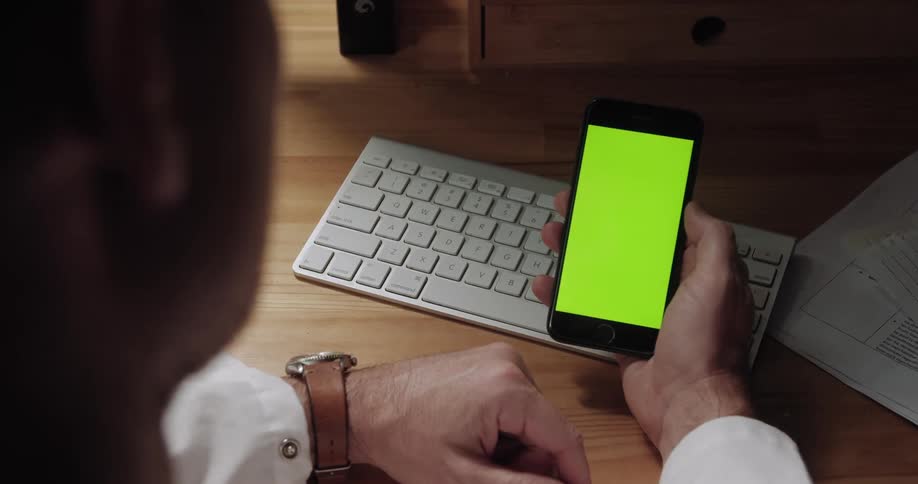 Businessman sitting at the table uses smartphone in the office