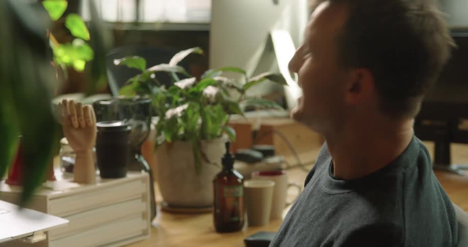 A man sits at this desk and video chats on his laptop