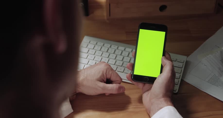 A man looks at a cell phone with a yellow screen