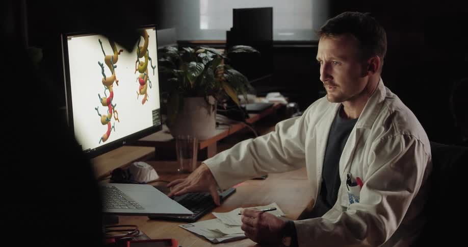 A doctor works on a laptop at his desk