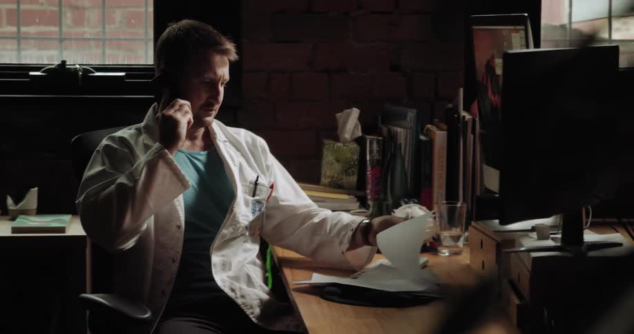 A man sits at his desk and talks on the phone