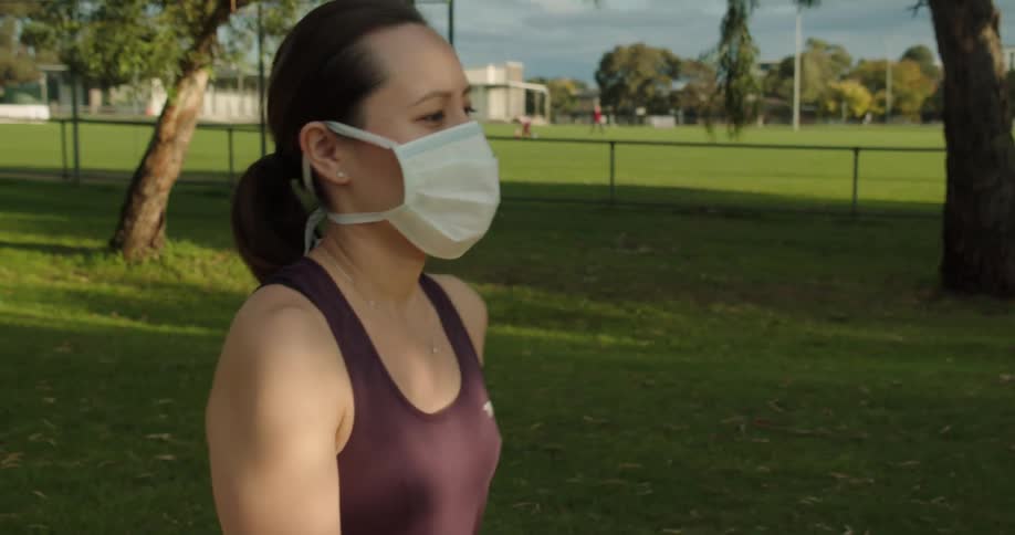 A young woman wearing a mask walks outside