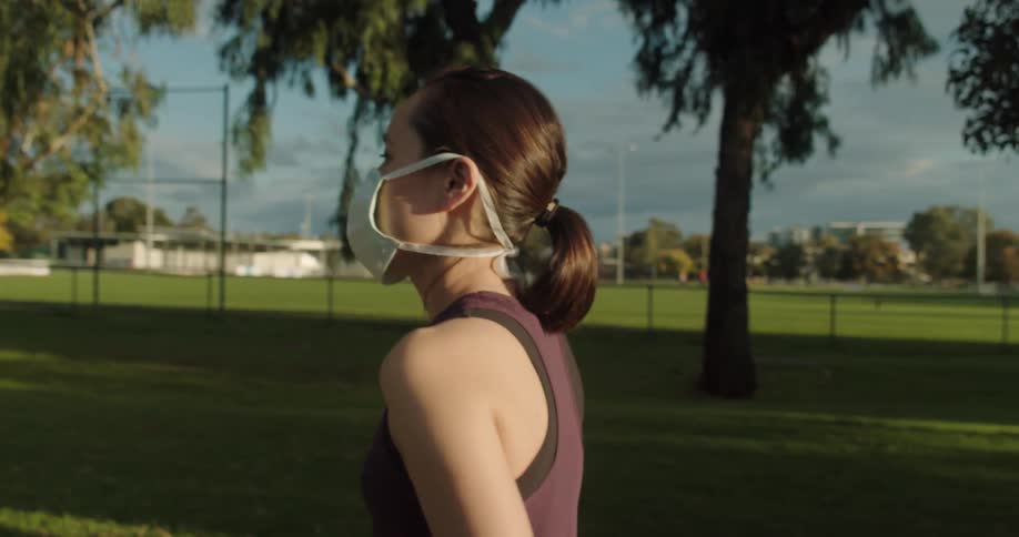 Woman in face mask and athletic apparel taking a walk