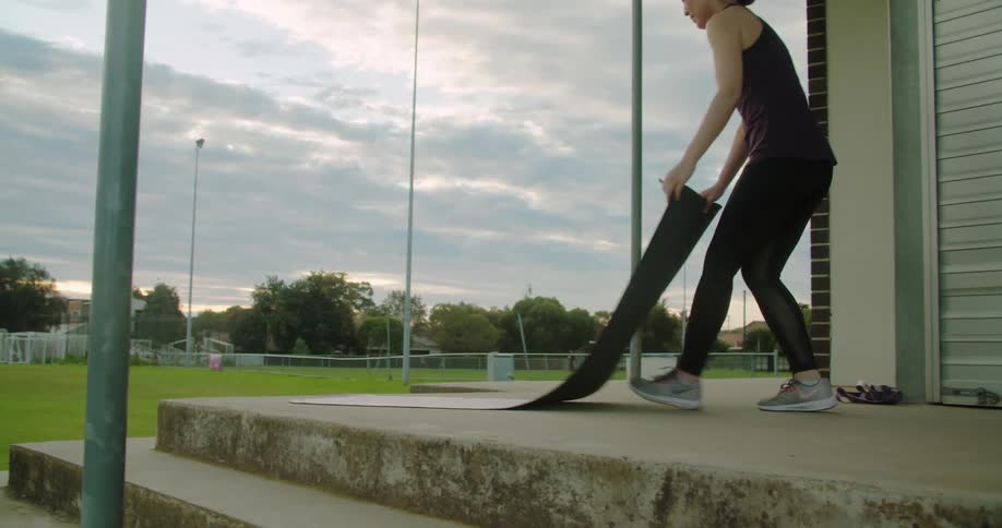 A woman rolls a yoga mat out