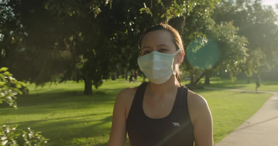 A woman walks down a path wearing a face mask
