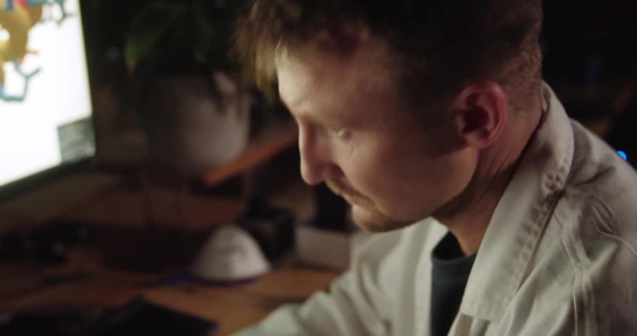 A doctor makes notes on a notepad and looks at a computer monitor