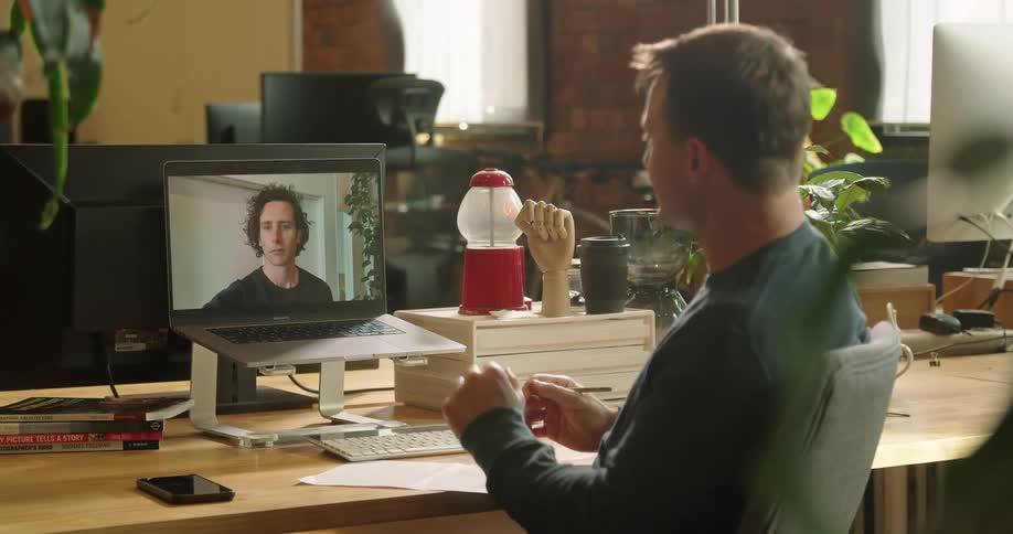 Man sitting at the desk makes a video call on the laptop in the office