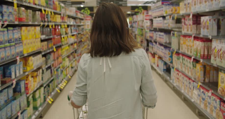 Woman walks down aisle of grocery store