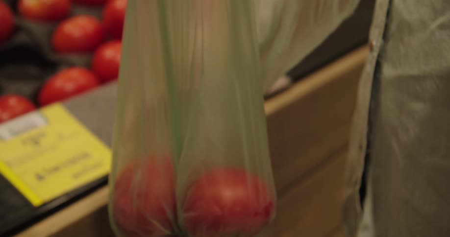 A woman puts tomatoes in to a bag