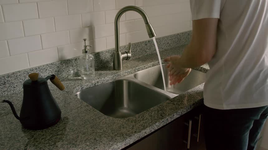 A person washes their hands in a kitchen sink
